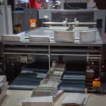Máquina pegadora de cajas plegadizas en funcionamiento en imprenta CDMX, ideal para servicios de pegado de cartón automático y eficiente.