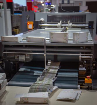 Máquina pegadora de cajas plegadizas en funcionamiento en imprenta CDMX, ideal para servicios de pegado de cartón automático y eficiente.